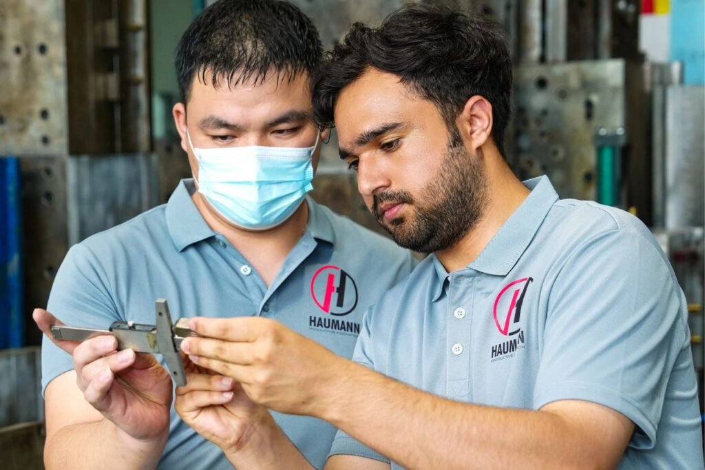 Two Haumann engineers inspecting a plastic component during quality control in the molding facility
