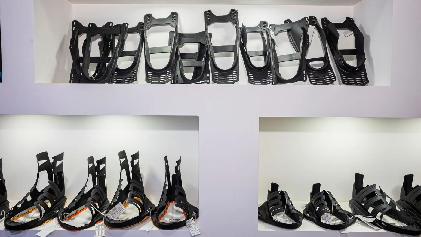 Rows of black injection moulded sports binding frames and footwear chassis components on display shelves